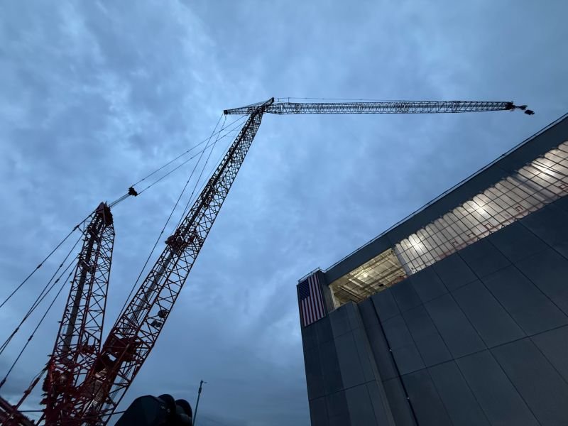 Red lattice boom crane beside a Virginia data center building under construction