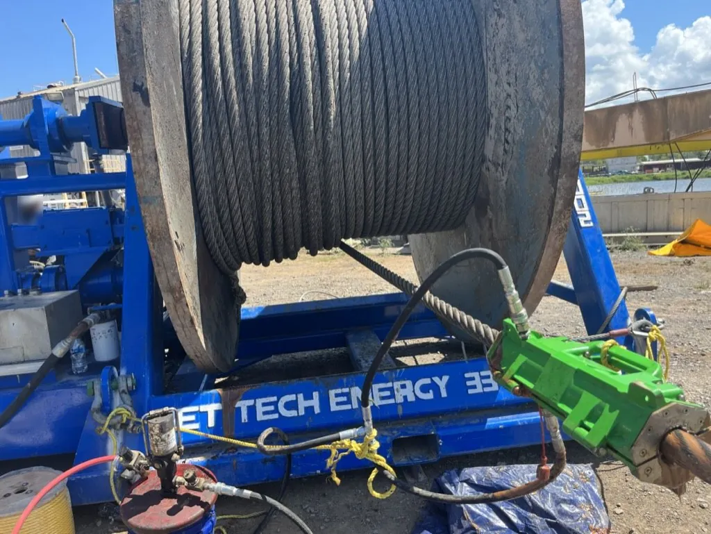 Wet Tech RS-002 spooling unit lubricating wire rope with the Viper lubrication system, a green lubricator clamped on the rope as it spools off a steel reel
